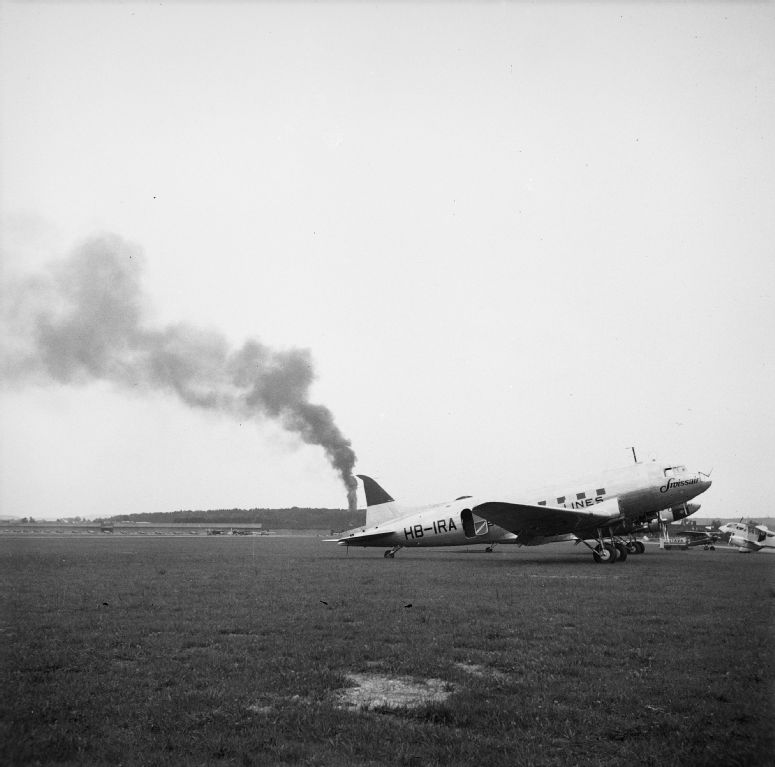 Douglas DC-3-216, HB-IRA with fire in the background